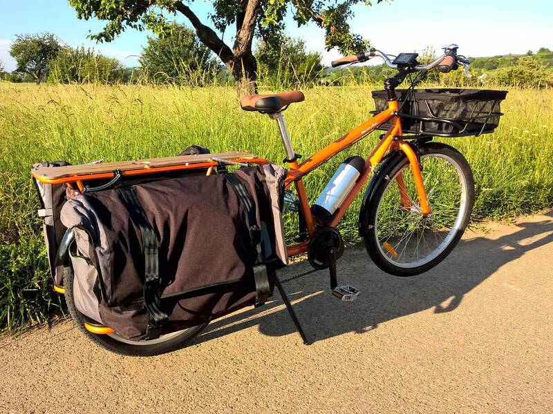 Ein Fahrrad mit Gepäckträger vor einer Wiese.