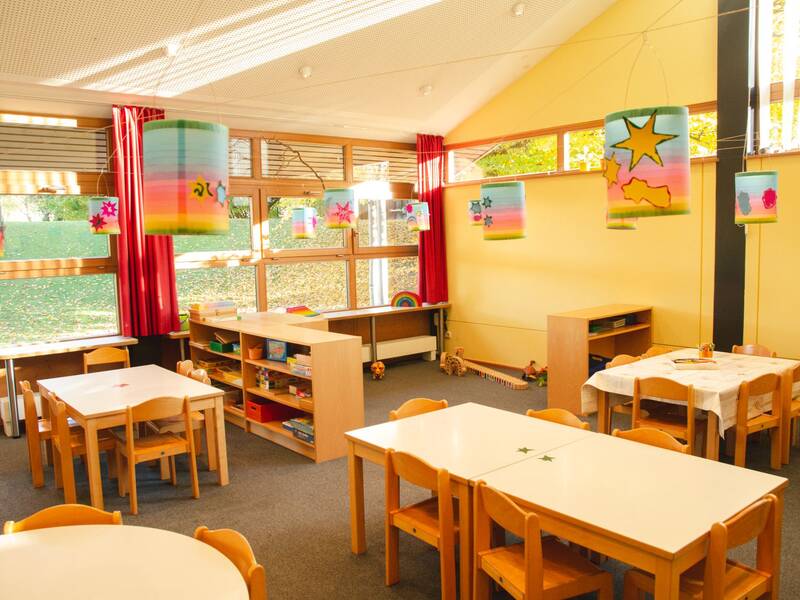 Innenraum des Kindergartens Mariä Himmelfahrt in Bad Aibling mit Tischen und Stühlen.